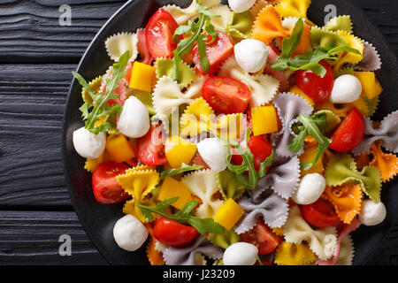 Pâtes farfalle multicolores avec des tomates et mozzarella close-up sur la table horizontale vue du dessus. Banque D'Images