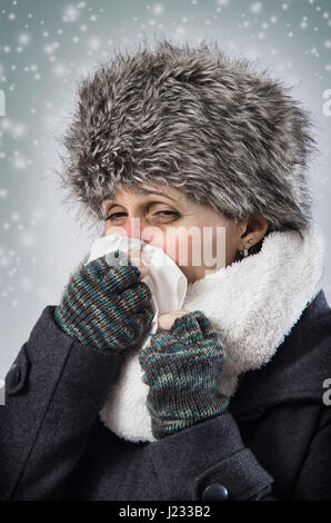 Femme malade avec des vêtements chauds soufflant son nez sous la neige de l'automne Banque D'Images