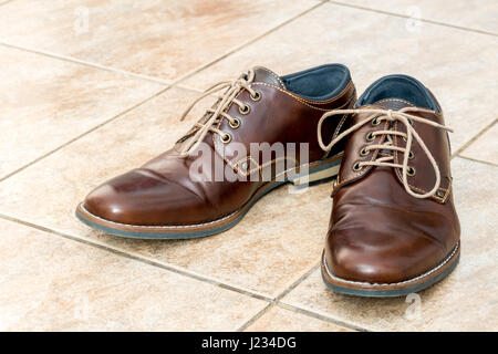 La mode chaussures pour hommes en cuir brun sur un carrelage en céramique brun clair Banque D'Images