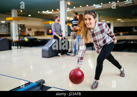 Belle femme bowling avec des amis s'apprête à jeter ball Banque D'Images