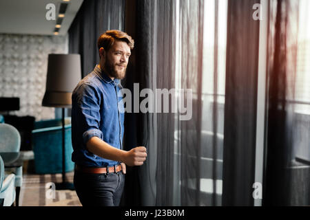 Handsome man enjoying view de la luxueuse chambre d'hôtel Banque D'Images