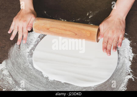 Femme à l'aide de rouleau à préparer le glaçage royal pour la décoration de gâteau, mains détail Banque D'Images