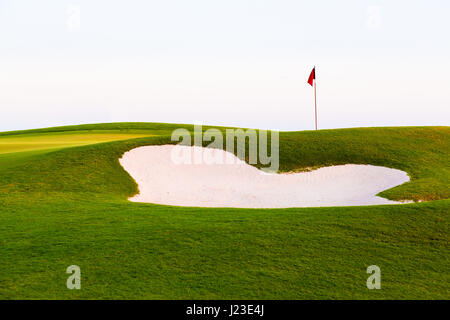 Drapeau rouge de trou de golf au-dessus de fosse de sable ou le parcours de golf bunker Banque D'Images