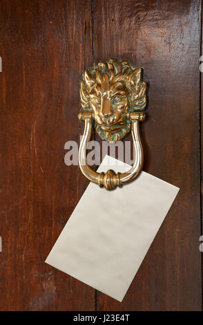 L'enveloppe vide avec de l'espace pour le texte placé sous une tête de lion en laiton heurtoir de porte ancien en chêne Banque D'Images