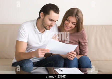 Jeune couple reading termes et conditions avant de signer un contrat Banque D'Images