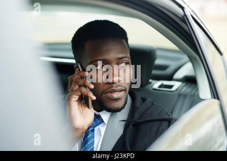 African-american businessman driving car and talking on cellphone Banque D'Images