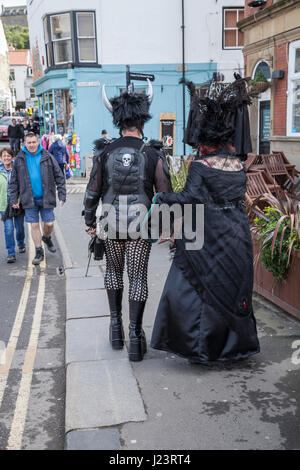 Un homme et une femme habillés comme des Goths marchant à travers les rues à la Whitby Goth Week-end à North Yorkshire, Angleterre, Royaume-Uni Banque D'Images