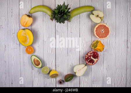 Fresh Fruits tropicaux mûrs placé sur une planche de bois blanc maling une forme de coeur Banque D'Images