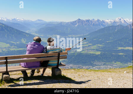 Deux hommes assis sur un banc de bois en admirant la vue panoramique sur les montagnes de Hafelekarspitze, Tirol, Autriche Banque D'Images