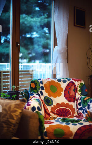 Scène calme d'un fauteuil en face de fenêtre par des rideaux décoratifs. Banque D'Images