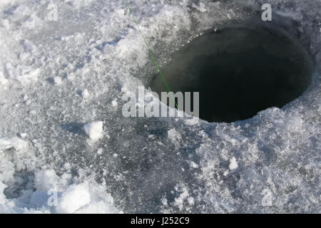 La glace fraîchement nettoyée trou de pêche prêt à définir. Banque D'Images