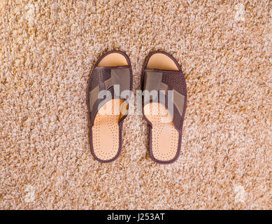 Chaussons pour hommes en cuir stand au milieu d'un tapis beige flanelle Banque D'Images