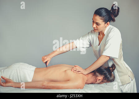 Gua Sha, Massage Therapy. Une jeune femme professionnelle rend masseur massage Thaï. Le patient est allongé sur un lit et est recouvert d'une serviette blanche. Trea Banque D'Images