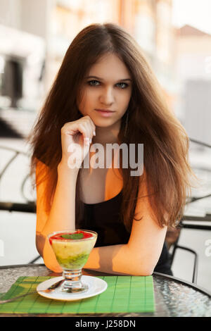 Jeune femme avec ice cream at sidewalk cafe Banque D'Images