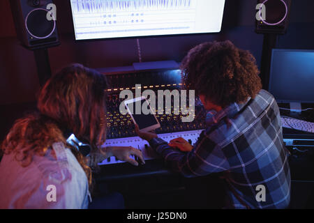 Les ingénieurs audio mâle using digital tablet in recording studio Banque D'Images