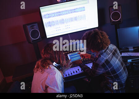 Les ingénieurs audio mâle using digital tablet in recording studio Banque D'Images