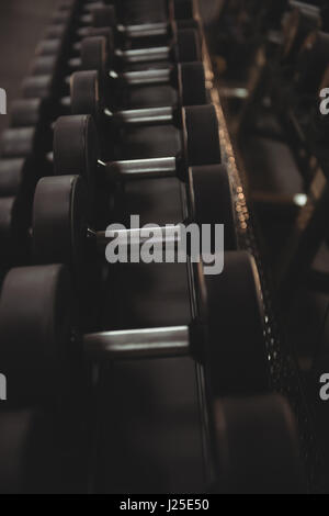 Les haltères disposées sur une grille dans la salle de sport Banque D'Images