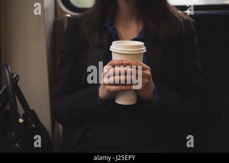 Midsection of woman holding cup alors qu'il était assis dans le train Banque D'Images
