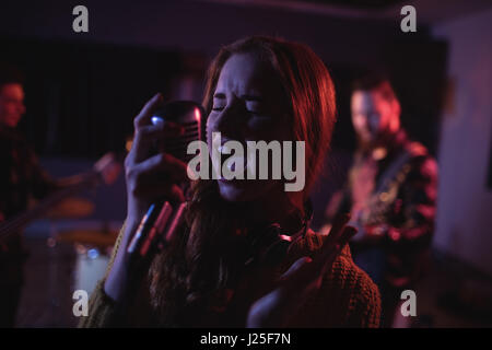 Woman singing on retro microphone en studio d'enregistrement Banque D'Images