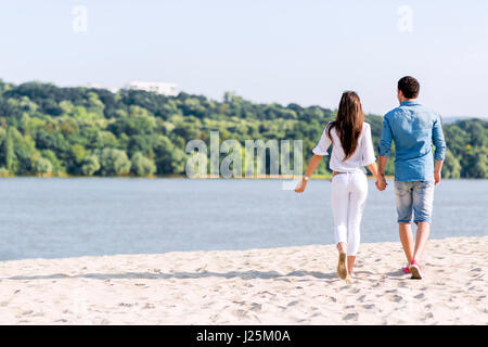 Couple holding hands and walking on a sandy beach Banque D'Images