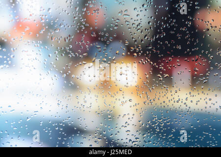 Gouttes de pluie sur la fenêtre d'une voiture avec de magnifiques arrière-plan flou de feux de circulation de la rue Banque D'Images