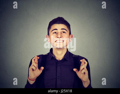 Jeune homme faisant un souhait garder ses doigts croisés. Le langage du corps Banque D'Images