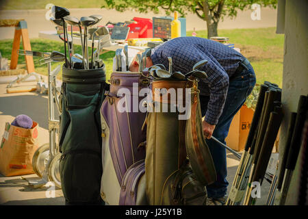 Une vieille Caucasian man looks at clubs de golf à une vente de garage ou de braderie à Oklahoma City, Oklahoma, USA. Banque D'Images
