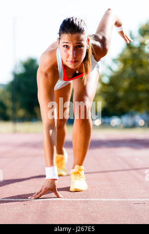 Belle femme sprinter se préparer pour l'exécuter au cours de l'été Banque D'Images