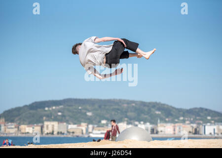 Les enfants sautent très haut sur une plage et faire tourner dans le flip off air sauts acrobatiques Banque D'Images