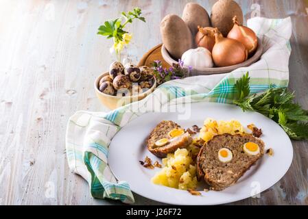 Photo horizontale avec portion de viande faits maison à base de porc et de boeuf de la viande hachée et remplis par des oeufs de cailles sur plaque blanche avec prise constante de pommes de terre. Autres Banque D'Images