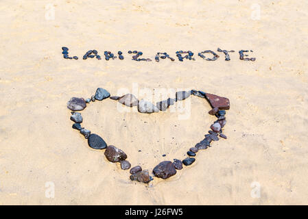 Mot Lanzarote et un coeur écrit avec les pierres noires sur une plage de sable doré Banque D'Images