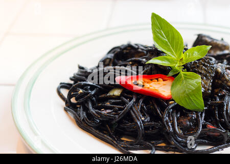 Noir italien spaghetti avec anneaux de calmars et moules sur tableau blanc. Banque D'Images