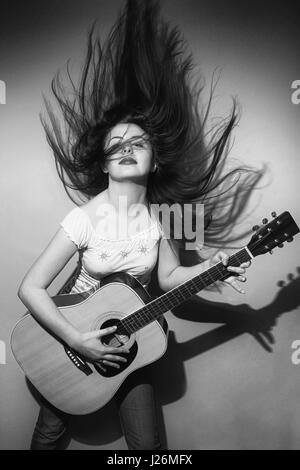 Jeune femme brune secouer ses cheveux et passionnément à la guitare. Banque D'Images