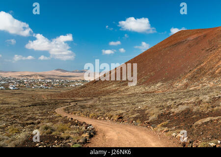 Vue sur le village de Lajares Fuerteventura, Espagne avec un chemin de terre sinueux menant au-delà de la Montana Colorada dans l'image. Banque D'Images