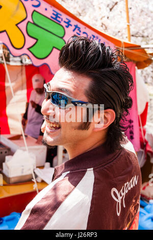 Le Japon, Shukugawa. L'homme japonais avec mod-Anglais look rocker, geased les cheveux en arrière, lunettes de soleil, la moitié se tournait pour faire face. Close up. Banque D'Images