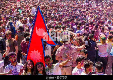 Des milliers de jeunes, les bavures et en jouant avec la couleur, célèbrent le festival de holi et brandissant le drapeau national népalais Banque D'Images