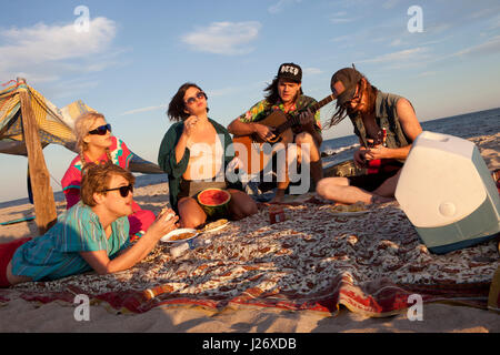 Amis jouant de la musique ensemble sur une plage Banque D'Images