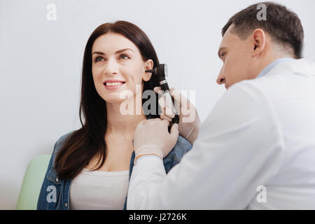 Médecin attentif examen de l'oreille faisant de jolie femme Banque D'Images