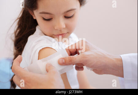 Blessure à l'épaule. Professionnel Nice male doctor holding un plâtre et le mettre sur les filles pendant le traitement de sa blessure à l'épaule Banque D'Images