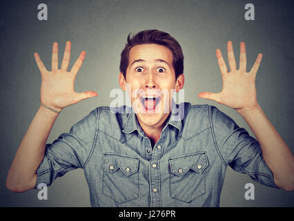 Heureux jeune homme fou criant super excité surpris isolé sur fond gris Banque D'Images