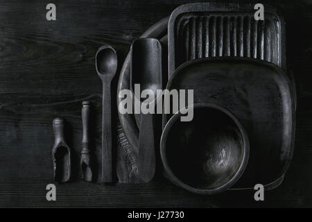 En bois brûlé noir vide ustensiles de cuisine, plaques, scoop et déposer sur fond de bois noir. Mise à plat avec l'espace Banque D'Images