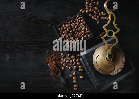 Les grains de café torréfiés et moudre le café dans la boîte en bois avec vintage coffee grinder et scoop sur fond gravé en bois noir. Vue de dessus avec l'espace. Banque D'Images