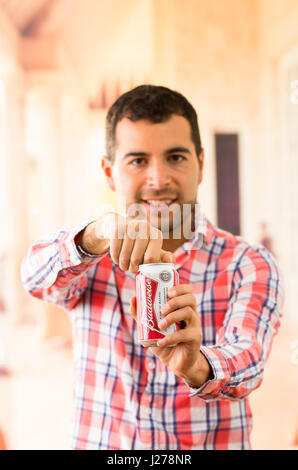 Young man smiling ouvrant un Coca Cola peut Banque D'Images