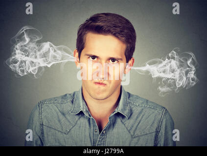 Closeup portrait de jeune homme en colère, soufflant de la vapeur qui sort des oreilles, à propos d'avoir isolé nerveuse fond gris. Les droits de l'emotio négatif Banque D'Images