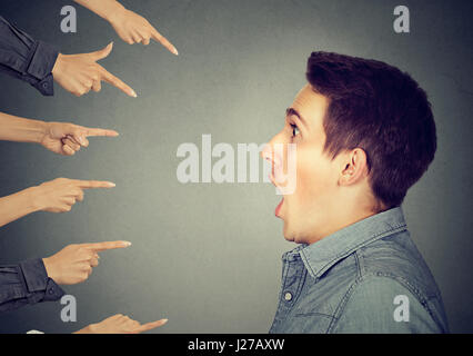 Concept d'accusation coupable personne guy. Profil côté choqué man de doigts pointant sur lui isolé sur fond de mur gris. Visage humain Banque D'Images