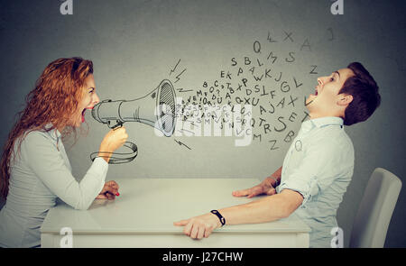 Jeune femme en colère avec mégaphone criant à souligné l'homme effrayé époustouflé par vague de lettres de l'alphabet Banque D'Images