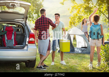 Young happy couple on camping trip dire bonjour amis arrivés Banque D'Images