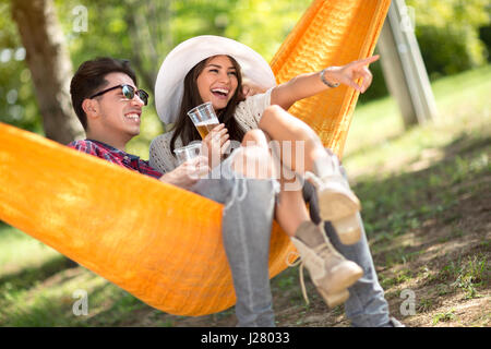 Smiling girl in hammock show avec doigt quelque chose à son petit ami dans les bois Banque D'Images