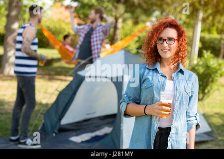 Jeune femme rousse avec des lunettes en bois avec verre de bière Banque D'Images