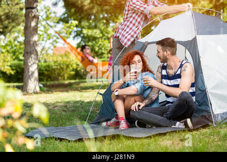 Les hommes et les femmes à l'été, des boissons Bière en face de tente en forêt Banque D'Images